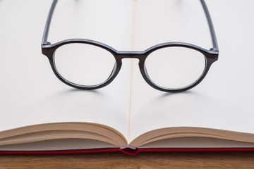 Black glasses on notebook on the table with blurred background. Close-up glasses.