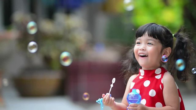 Asian little cute girl or kid blow air soap bubbles with smile. happiness,fun and childhood concept .