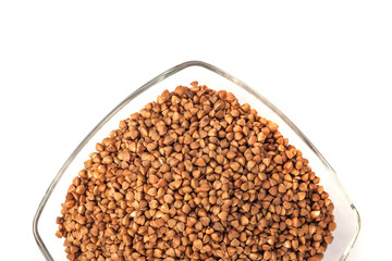 Roasted buckwheat grains in glass bowl isolated on white background