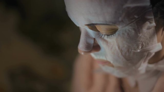 Close-Up Face of a Woman in a Rejuvenating Mask Looks at the Smartphone Screen