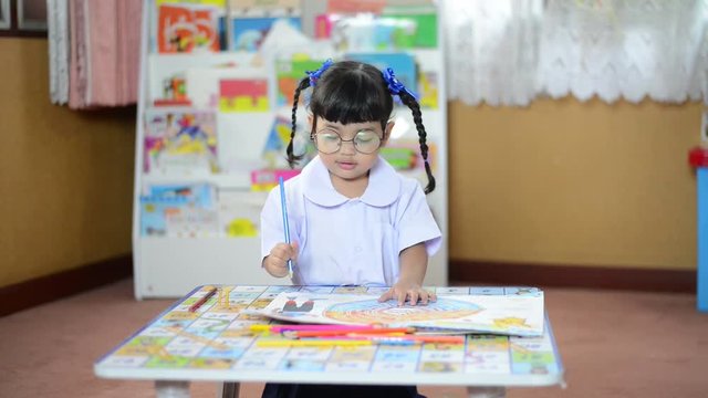 A cute little child Asian school girl doing homework and  learn how to painting color. Kid enjoy learning with happiness at school. Clever,Education and smart learning concept