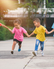 group of asian children holding hands and running or walking together on walkway at school