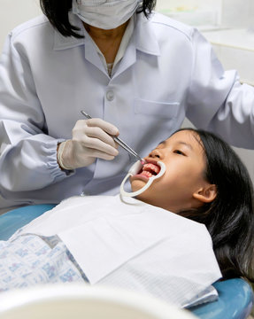 Close Up Of Young Asian Girl White Teeth With Retractor In Dental Office. Kid Met The Dentist For Routine Dental Checkup Or Examination And Fluoride Treatment. Fluoride Application Process.