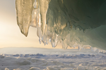 View from Ice Cave through sparkling stalactite on sunset. Lake Baikal