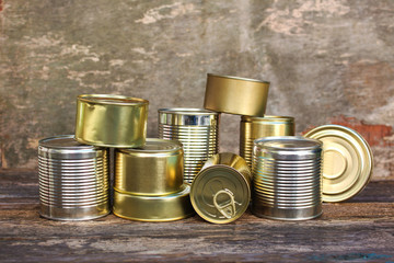 Different closed canned food on old wooden background.
