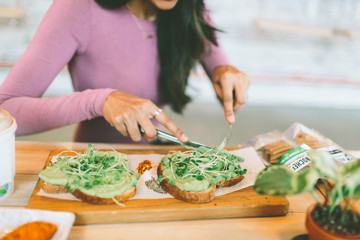 A woman cutting a piece of avocado toast. 