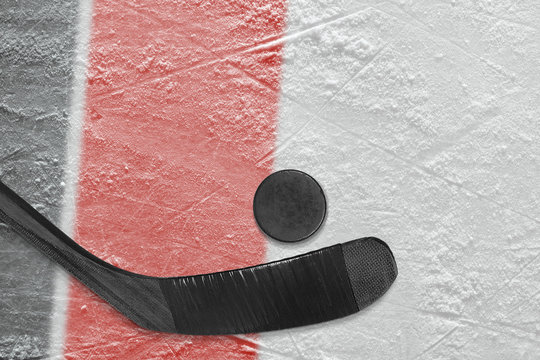 Hockey stick, puck and fragment of the ice arena with black and red lines