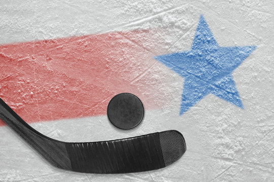 An image of a red line with a blue star on ice and a stick with a puck