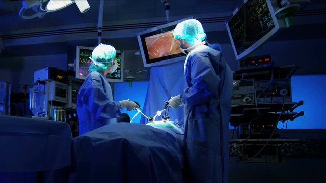 Medical team in scrubs in the operating theater of multi ethnic origin using an Endoscopy to specialise in Laparoscopy surgery via camera technology 