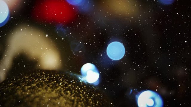 Video composition with falling snow over blurry video with lights and golden bubble