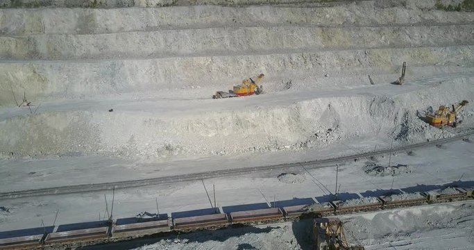 big power digger operates loading ore train with asbes