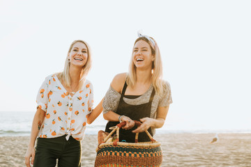 Friends walking at the beach with a picnic basket