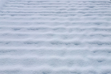 Stairs on the boardwalk covered with fresh snow without footsteps.