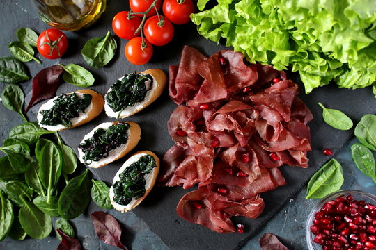 Healthy diet food concept. Iron on the food. The bruschetti with spinach, bresaola and pomegranate. Diet food. Top view with copy space.