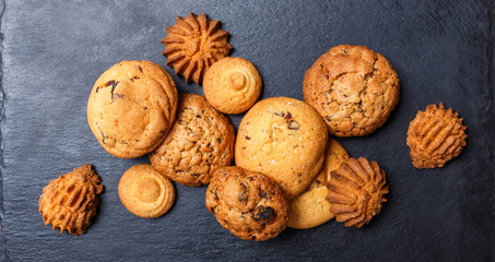 Assorted cookies with chocolate chip, oatmeal raisin on stone slate background on wooden background close up. Homemade baking. Top view, flat lay