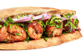 Grilled meat in sandwich with onion and greens on white background. Shashlik or Shish kebab popular in Eastern Europe. Hot meat dishes