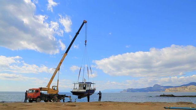 crane lifts the blue boat from the water