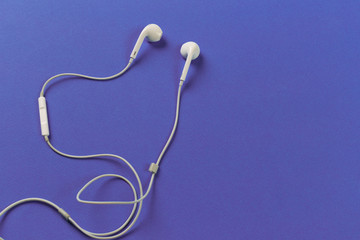 White earphones on violet background