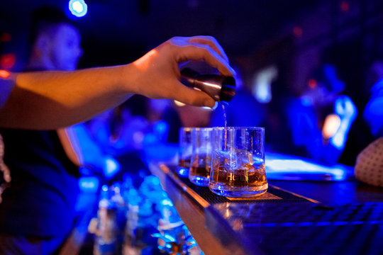 barman at work, pouring spirit into a glass. concept about professions and drinks