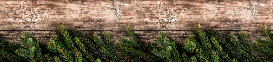 Creative layout frame made of Christmas fir branches on wooden background. Xmas and New Year theme. Flat lay, top view, wide composition
