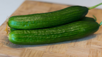 Fresh cucumbers on the bamboo cutting board closeup