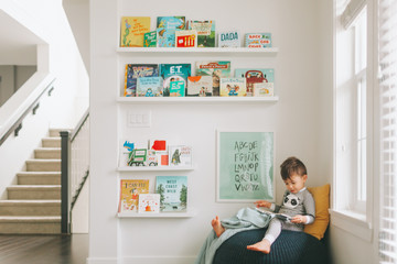 A little boy reading in a reading corner of his play room. 