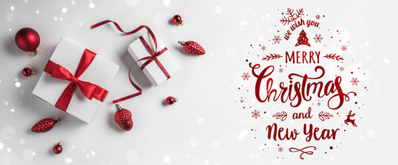 Merry Christmas Typographical on white background with gift boxes and red decoration. Xmas and New Year card, bokeh, light. Flat lay, top view