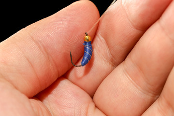 Feathers on the hook for fishing in the hand