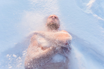 Naked man swiming in the snow in cold winter weather