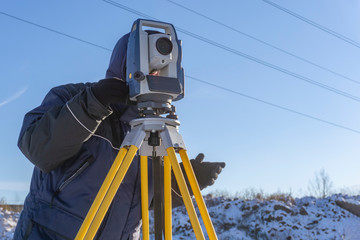 Topographer makes geodetic survey of the construction site for the inventory in winter