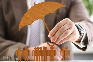 Businessman holds wood umbrella in hand