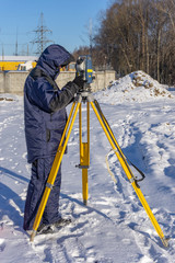 A surveyor enters the survey data for a cadastre at a construction site during the winter period.