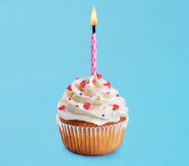 Cupcake with birthday candle on a blue background.