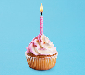 Cupcake with birthday candle on a blue background.