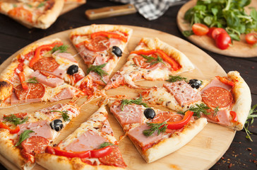 pizza, fresh pizza with mozzarella, tomatoes, ham and cheese. Italian pizzeria. Fresh pizza on the kitchen table
