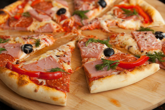 pizza, fresh pizza with mozzarella, tomatoes, ham and cheese. Italian pizzeria. Fresh pizza on the kitchen table
