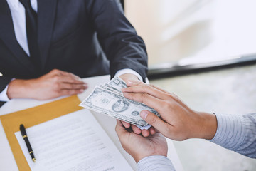 Bribery and corruption concept, bribe in the form of dollar bills, Businessman giving money while making deal to agreement a real estate contract