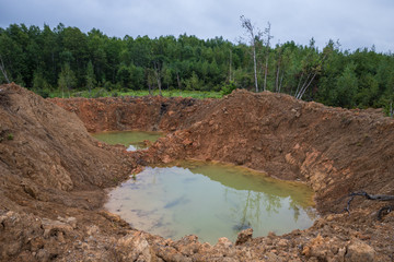 Hole on ground from powerful explosion. Bomb crater in the forest. Disposal of explosives.