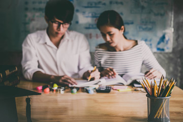 Fototapeta premium High school or college Asian student group sitting at desk in class studying and reading, doing homework and lesson practice preparing exam to entrance, education concept