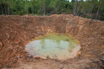 Hole on ground from powerful explosion. Bomb crater in the forest. Disposal of explosives.