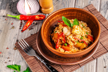 Concept of Spanish cuisine. Paella with seafood and shrimps, with green peas in a clay plate. A glass of cool wine is on the table.