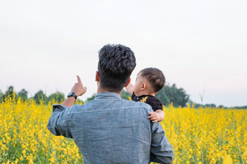 Father and baby together at sunn hemp field in Chiang Rai, Thailand / Both father and child fingers pointing forward