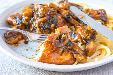 Italian cuisine - Marsala chicken with mushrooms and spaghetti on a plate, close-up, rustic style