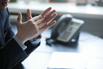 close up of hands gesturing while holding pen and torso of man with business suit and blue tie