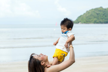 Mom with her son play on the sea shore.