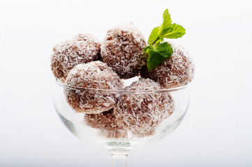 Hand-made sweets made from coconut, almond nuts and banana in a glass on a white background. Macro shooting. Tasty and healthy fitness food. Dietary snacks
