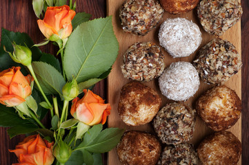Hand-made sweets made from dried fruits, nuts and seeds (without sugar). Macro shooting. Near orange roses. Delicious and healthy fitness candy