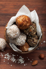 Useful fitness sweets from dried fruits, nuts and seeds, without sugar in the shell of coconut on a wooden brown board. Vegan, vegan concept