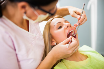 Young woman at dentist. Dentist is examining her teeth.