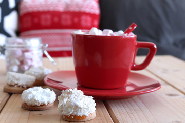 Hot cocoa with marshmallow in a red ceramic mug on a wooden table and home made fresh baked Christmas cookies. The concept of holidays and New Year.